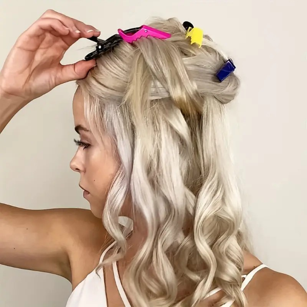 Woman with styled hair using colorful clips on a plain background