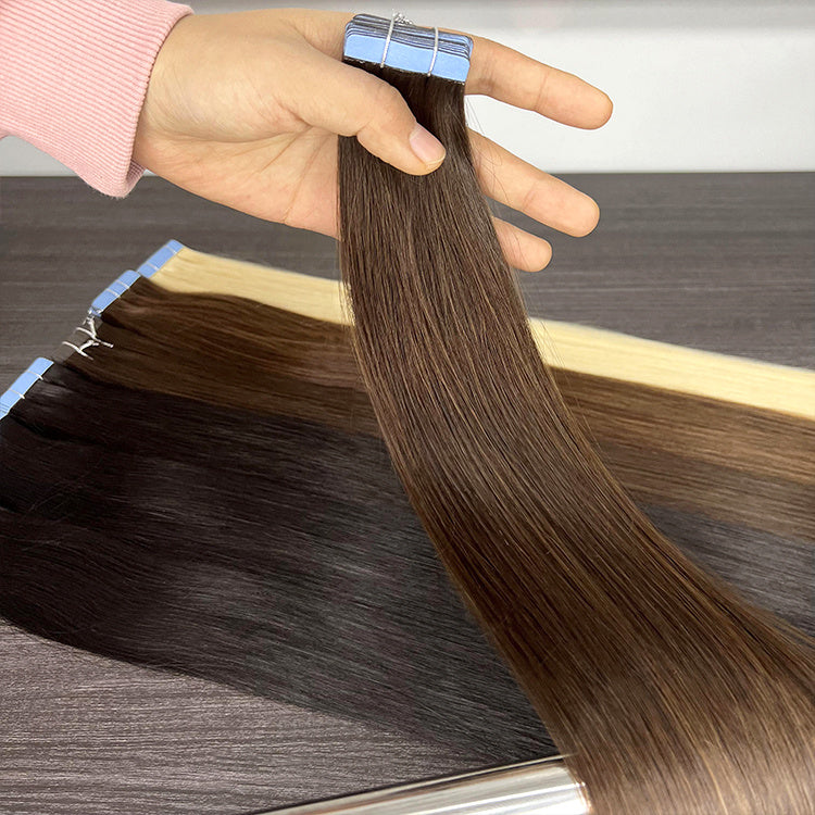 Brown hair extensions held by a hand on a wooden surface
